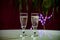 Pouring of brut champagne, cava or prosecco wine in glasses with garland lights on dark background, new year or birthday party