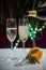Pouring of brut champagne, cava or prosecco wine in glasses with garland lights on dark background, new year or birthday party