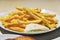 Pouring cheese sauce on french fries, closeup