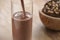 Pouring chocolate milk in glass with homemade chocolate cookies with hazelnuts on background