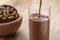 Pouring chocolate milk in glass with homemade chocolate cookies with hazelnuts on background