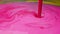 Pouring colorful pink paint on surface with yellow patterns