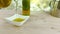 Pouring cooking olive oil in the bottle in the white container on wood table background near olive oil bottle, slow motion