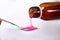 Pouring cough syrup into spoon on white background