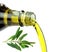 Pouring extra virgin olive oil from glass bottle with green olive branch