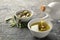 Pouring of fresh oil into bowl with olives on table