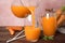 Pouring freshly made carrot juice into glass on wooden table