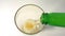 Pouring gold colour, fresh, cold beer from green bottle into glass angle side view many bubbles,  flowing white foamy wheat or lag