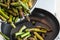 Pouring green asparagus into a pan with warmed sunflower oil