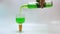 Pouring a green liqueur drink from glass bottle to authentic cup