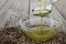 Pouring hemp oil into glass bowl and hemp seeds on wooden background