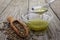 Pouring hemp oil into glass bowl and hemp seeds on wooden background