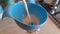 Pouring home made plant milk in a glass bottle