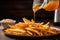 pouring homemade fries onto a plate