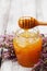 Pouring honey in jar and flowers heather on wooden rustic background.