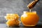 Pouring honey in jar and honeycomb on black table