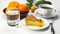 Pouring honey on a piece of lemon orange sponge cake in white ceramic dish on white table.