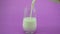 Pouring milk in glass from a bottle milk glass on purple colorful background Glass of milk in slow motion