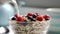 Pouring milk from jug onto bowl of healthy breakfast muesli