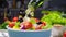 Pouring Olive oil on fresh Vegetable salad, Greek salad on white table