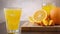 Pouring orange juice in glass with ice cubes on background fresh orange fruit