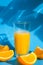 Pouring orange juice stream from jug into glass of squeezing Orange juice with sliced fruits on blue background. Fruit