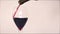 Pouring red wine into an empty tear drop shaped wine glass