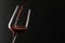 Pouring red wine into glass on dark background