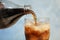 Pouring refreshing soda drink into glass on background, closeup