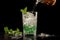 pouring soda into mojito glass with ice cubes