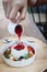 Pouring a strawberry syrup to pannacotta