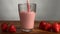 Pouring strawberry yogurt or smoothie in glass on wooden table