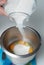 Pouring Sugar over Raw Eggs in Metal Bowl. Preparation of Dessert. Steb by Step cake making.