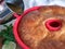 Pouring the syrup over freshly-baked rum baba in silicone cake mold. Rum-soaked circular cake Savarin