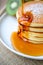 Pouring syrup on stack of pancake on white plate and sackcloth w