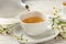 Pouring tasty chamomile tea into cup on wooden table