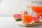 Pouring tasty freshly made grapefruit juice into glass on white wooden table. Space for text