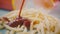 Pouring tomato sauce over pile of french fries or deep-fried potatoes, close-up slow motion shot