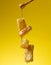 Pouring transparent sweet honey from a wooden stick on a wax honeycomb. Yellow background