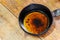 Pouring used cooking oil from frying pan on wooden table in kitchen