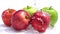 Pouring water on the red and the green apples on white background