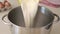 Pouring wheat flour into a stainless steel bowl to prepare dough for baking pastry