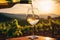 Pouring white wine into glass on vineyard background at sunset. Generative AI