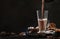 Pouring winter hot chocolate cocoa drink into tall glass with ispices on black table. Dark blue background. Copy space