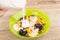 Pouring yogurt in green bowl with muesli