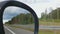 POV of car passenger, roadside landscape reflected in side view mirror, driving