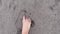 POV close-up footage of barefoot person walking on a beach with grey sand. Explore Canggu area in Bali island.