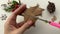 POV close-up footage of cutting a Christmas star out of old cardboard brown paper on white table with Xmas decor