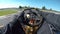 POV: Driving a go-kart in a black suit through sharp bends of a bumpy racetrack.