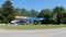 POV driving street pan Sunoco\\\'s station and cars at pumps clear blue sky